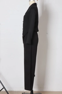 Detail of black two-piece suit showing the tailored sleeve and side profile of trousers