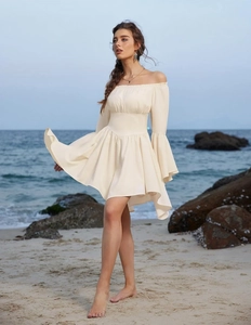 Détail d'une mini-robe crème à épaules dénudées avec manches cloche et jupe plissée de plage