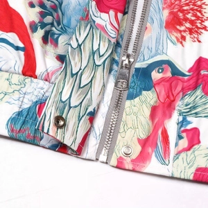 Close-up of vibrant floral print jacket with silver metal zipper and snap button details