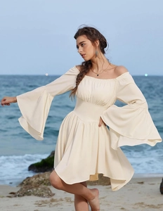 Détail d'une élégante robe crème à épaules dénudées avec manches cloche et ourlet à volants