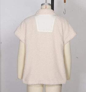 Detail of beige fleece vest featuring back white woven fabric patchwork and collar