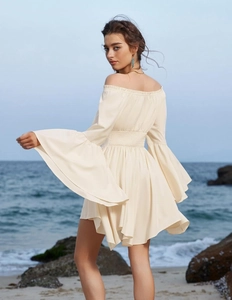 Détail de robe blanche à épaules dénudées avec taille smockée et manches évasées au bord