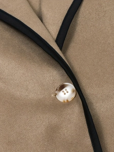 Detail of wool blend coat with contrast piping and marble textured button closure