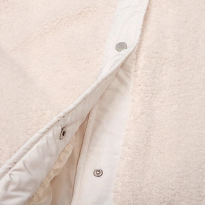 Close-up of cream wool vest featuring textured fleece fabric and silver metal snap buttons