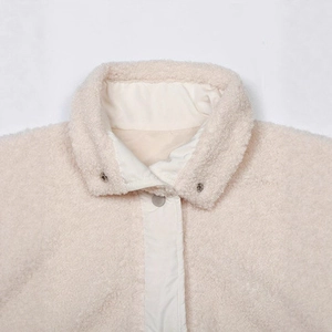 Detail view of the stand-up collar and metal snap button on this beige fleece vest coat
