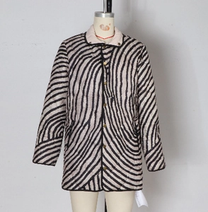 Détail d'une veste matelassée rayée pour femme avec bordure noire et boutons dorés