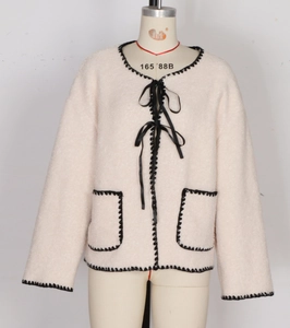 Detail of pink fleece coat featuring black ribbon bows and wavy crochet lace trim edges