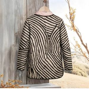 Détail d'une veste matelassée à vagues noir et blanc avec doublure de col rose sur cintre