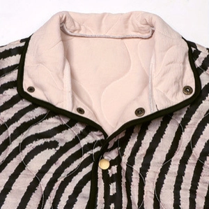 Détail d'une veste zébrée avec matelassage rose ondulé et boutons-pression en bronze