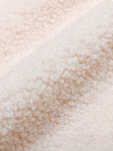 Close-up of thick beige sherpa wool vest fabric showing soft curly fleece texture