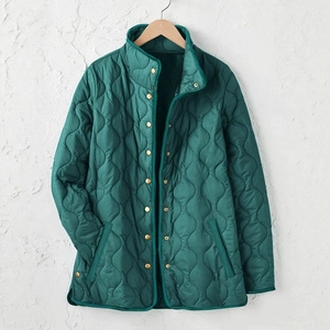 Detail einer dunkelgrünen Steppjacke mit Zwiebelmuster und goldenen Druckknöpfen