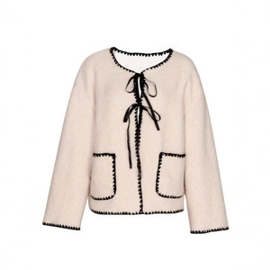 Detail of pink faux fur coat featuring black crochet trim and satin ribbon bow ties