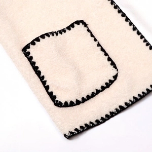 Detailed view of cream wool coat fabric featuring black contrast blanket stitch edging