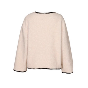 Detailed close-up of cream knit coat with decorative black contrast blanket stitching