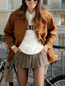 Women's brown faux suede lapel jacket with white sweatshirt and pleated mini skirt