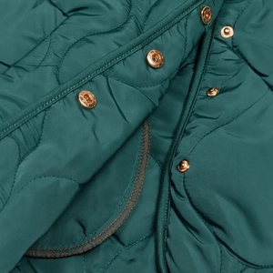 Detail der dunkelgrünen Steppjacke mit Zwiebelsteppmuster und roségoldenen Metallknöpfen
