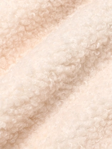 Macro shot of off-white sherpa wool texture showing soft and curly fiber details