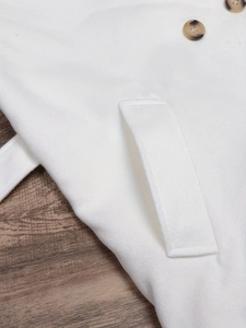 Close-up of white loose wool coat featuring tortoiseshell buttons and flap pocket