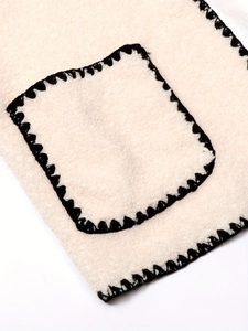 Chic cream-colored wool coat featuring black contrast stitching and a square pocket detail