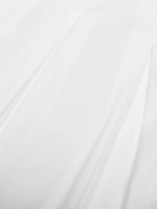 Close-up of high-waist white pleated skirt showing vertical fold details and fabric texture
