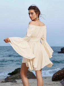 Robe mini crème à épaules dénudées et manches cloche oversize sur une plage ensoleillée