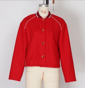 Detail of red varsity jacket featuring white piping and striped ribbed collar