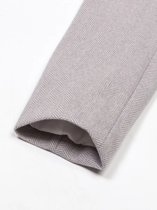 Detail of grey herringbone fabric texture and lining on the sleeve of a women's blazer