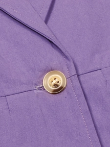 Detail shot of a purple linen blazer featuring a textured fabric and a resin button closure