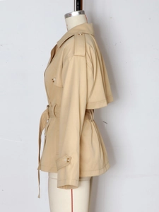 Detalle lateral de gabardina corta caqui con solapas clásicas y cinturón ajustable