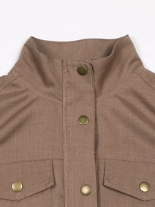 Macro detail of brown utility jacket with metallic snap buttons and high collar