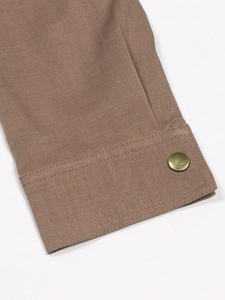 Detail of khaki twill jacket sleeve featuring a vintage brass button and neat stitching