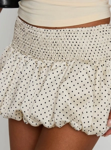 Detailed view of cream polka dot mini skirt with ruched elastic waist and satin texture
