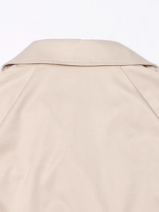 Detail van de beige trenchcoat-revers met strakke stiksels en fijne keperstof textuur