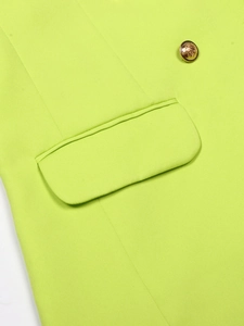 Detail of neon green blazer fabric showing flap pocket and ornate golden button