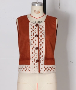 Dettaglio del gilet marrone vintage con pizzo bianco all'uncinetto e bottoni tondi scuri
