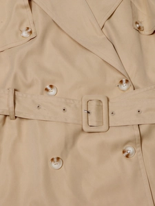 Detalle de los botones de doble botonadura y hebilla del cinturón de la gabardina beige