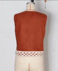 Dettaglio gilet vintage scamosciato marrone con rifiniture in pizzo bianco sull'orlo