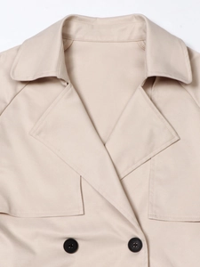 Detail van een beige trenchcoat met klassieke revers en hoogwaardige stikseltextuur