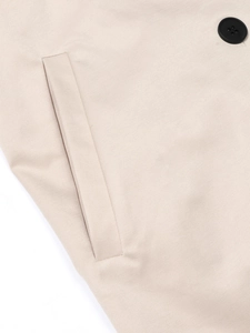 Detail van beige trenchcoat met twill stoftextuur, knoop en paspelzak