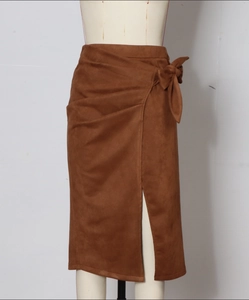 Detail of a brown suede wrap skirt featuring a side bow tie and front slit design