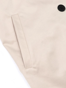 Vue détaillée du tissu du trench-coat beige avec bouton noir et coutures de poche