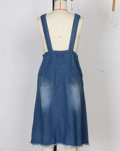 Detail view of denim overall dress back with symmetrical pockets and raw hemline finish