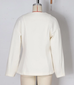 Detail of white long sleeve cropped blazer with tailored seams on textured fabric