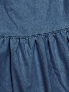 Detailed macro view of the blue denim fabric texture and ruffled seam craftsmanship