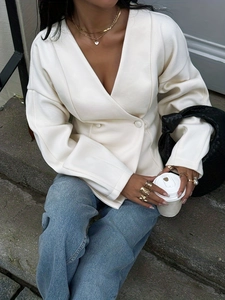 Minimalist white V-neck blazer for women styled with layered gold necklaces and woven bag