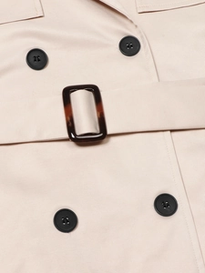 Détail d'un trench-coat beige avec boutons croisés et boucle en écaille de tortue
