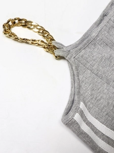 Détail macro du tissu gris côtelé avec chaîne dorée et rayures blanches latérales