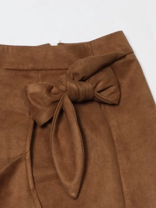 Detail of camel brown suede skirt featuring a soft texture and a stylish large waist bow