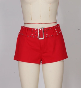 Detail of red punk shorts featuring a wide belt with silver metal rivets and square buckle