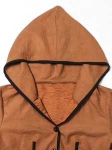 Detail view of brown textured hooded jacket featuring black trim and button closure